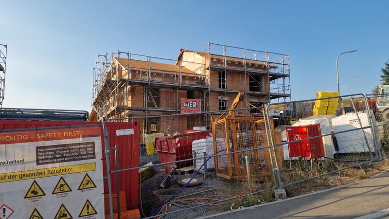 Ziegelrohbau mit Dachstuhl und Gerüst, Baustelle mit Absperrung