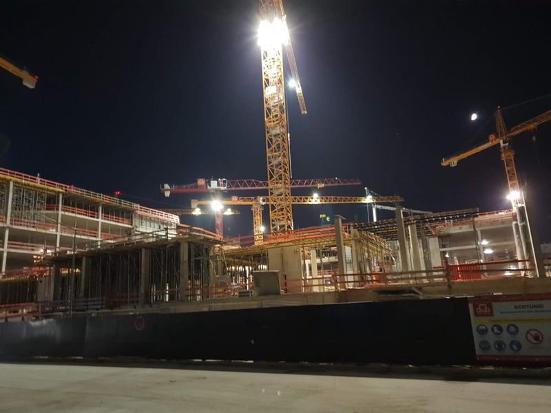 Beleuchtete Stahlbetonbaustelle bei Nacht mit mehreren Kränen