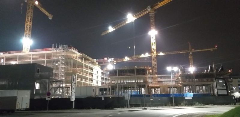 Rohbau bei Nacht mit Stützen, Schalung und Kränen