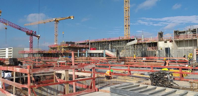 Stahlbeton-Rohbau mit Deckenschalung, Kränen und Arbeitern auf der Baustelle